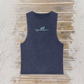 A sleeveless tank top in a washed navy blue color, featuring a small light gray graphic of a frenchy standing on a surfboard on the chest. The tank top is laid flat on a rustic wooden plank surface.