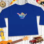 Blue sweatshirt with a colorful hand gesture design on a wooden surface with beach-themed items.