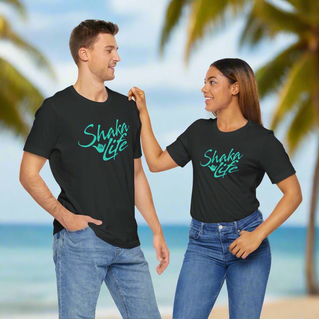 Two people wearing black t-shirts with 'Shaka Life' text on a beach.