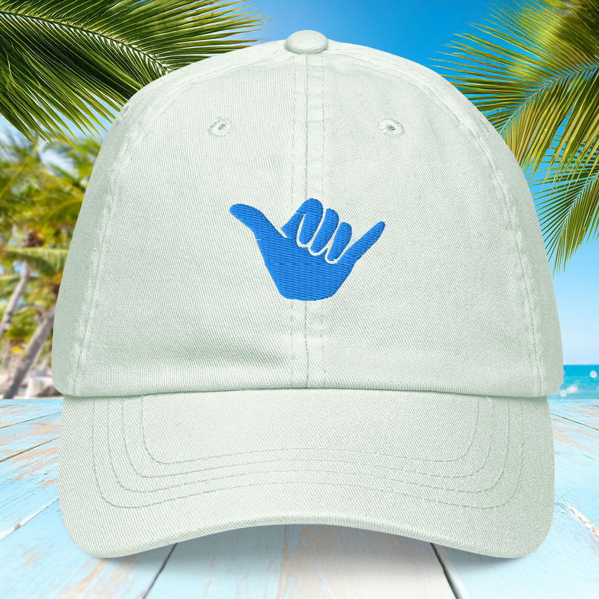 Pastel mint green cap with blue hand symbol on a beach background