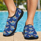 A person standing by a swimming pool wearing Shaka Surf slip-on water shoes with a blue background and a repeating multicolor Shaka hand graphic pattern.