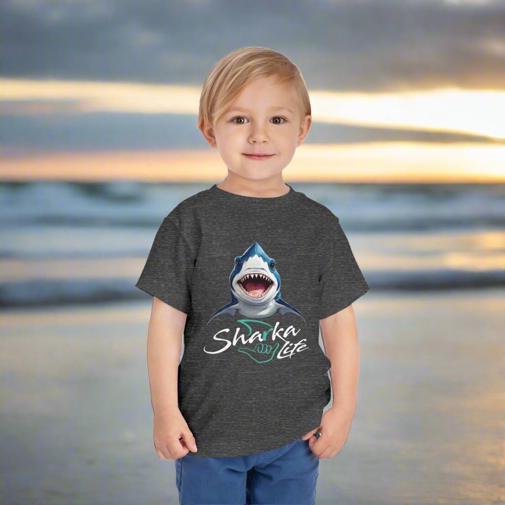Child wearing a dark gray Baby Shark t-shirt with a shark graphic and 'Sharka Life' text standing on Daytona Beach