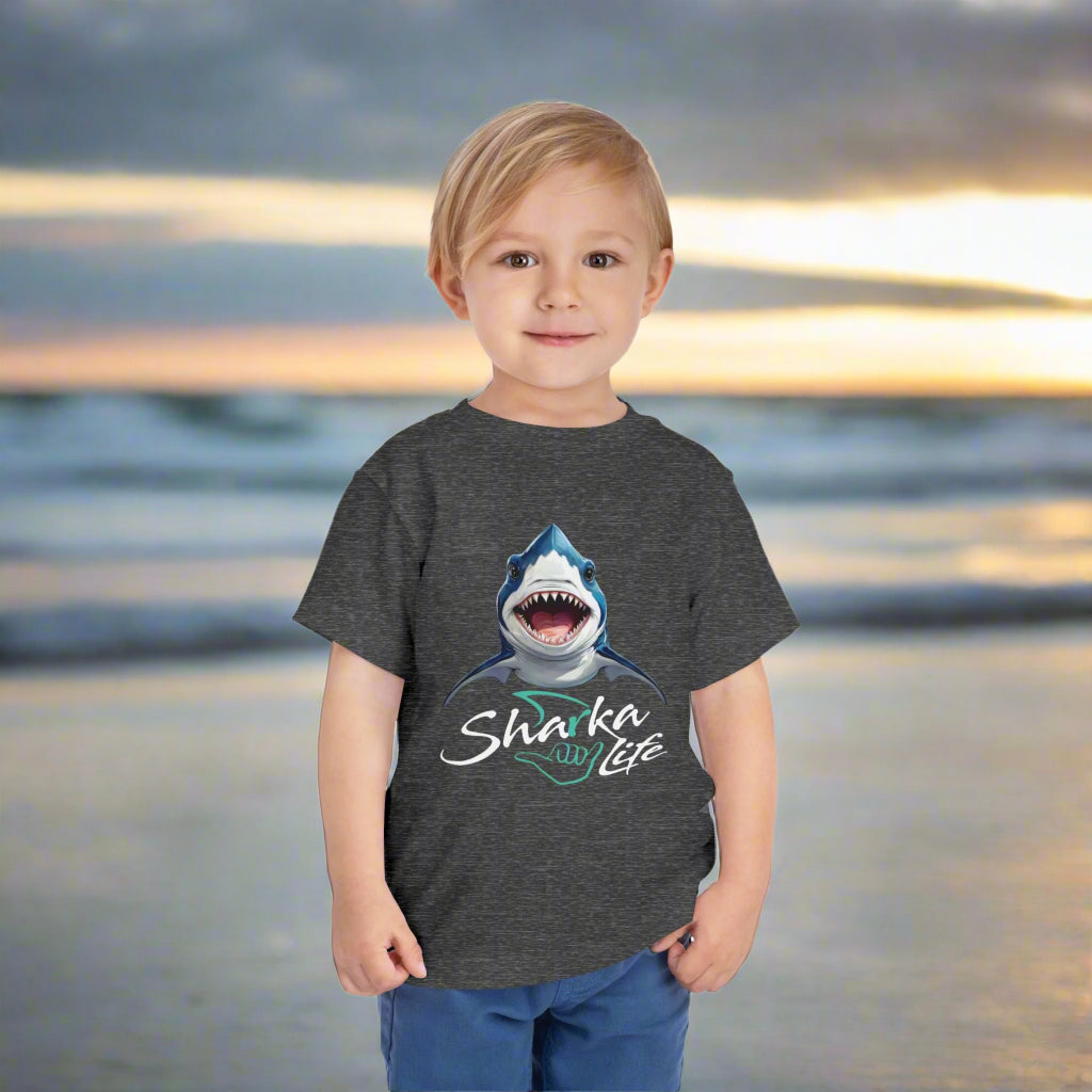 Child wearing a dark gray t-shirt with a shark graphic and 'Sharka Life' text standing on Daytona Beach