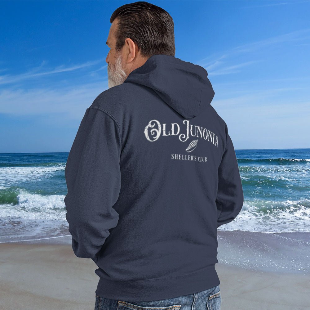 Man wearing a hoodie with 'Old Junonia' logo on a beach