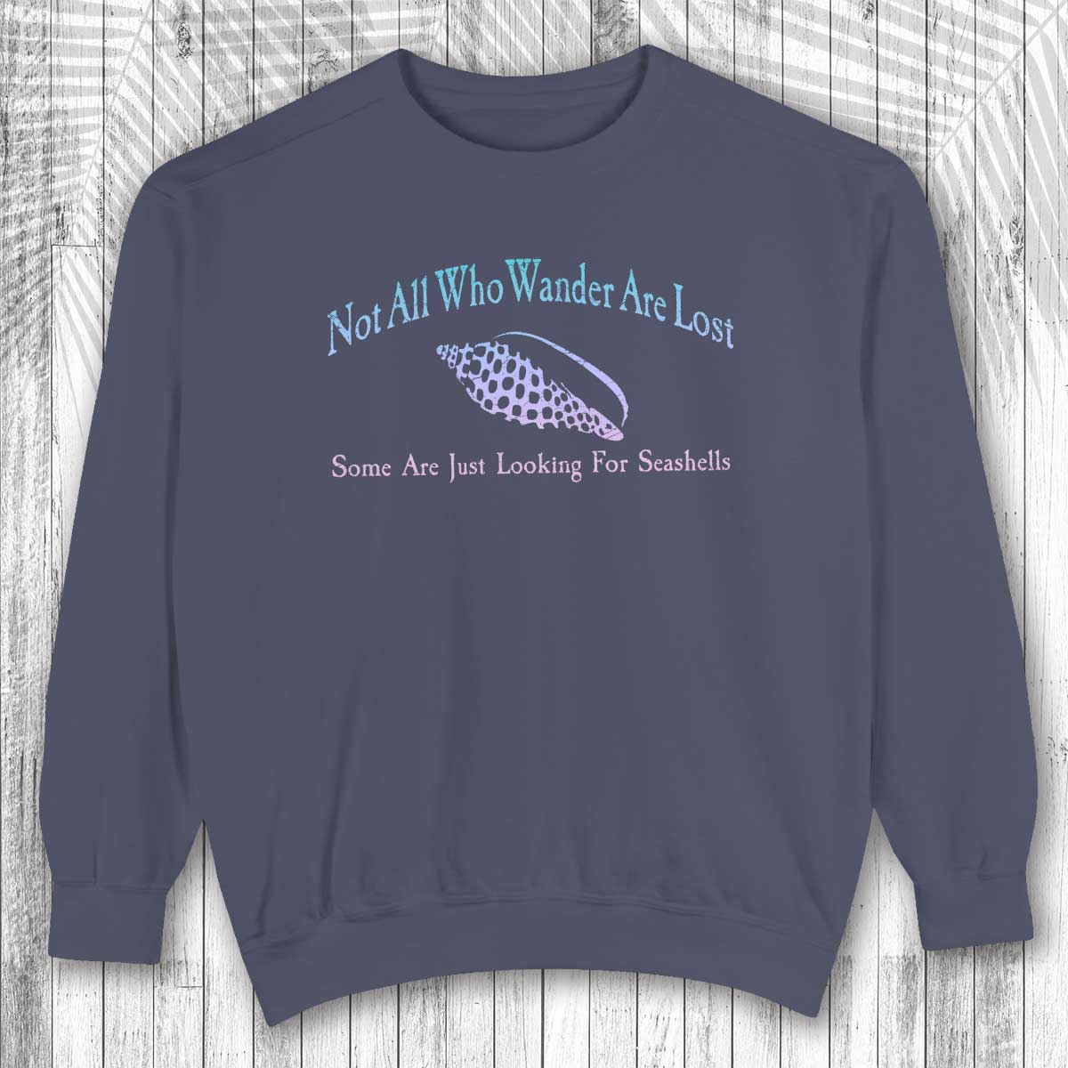 Navy blue sweatshirt with text and seashell graphic on a wooden surface