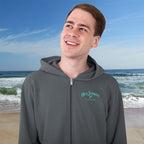 Person wearing a gray hoodie with a brand logo on a beach