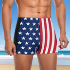 Person wearing American flag patterned swim shorts with a beach background