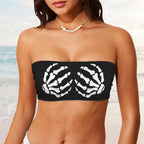 A woman wearing a black strapless bandeau-style top with a white skeletal hand print on each side of the front, shown against a plain white background.
