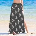 Woman wearing a black skirt with white skull and crossbones pattern on a beach.