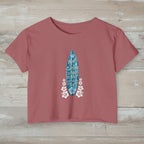 Smoked Paprika crop-top t-shirt with a blue surfboard graphic and text on rustic wood background