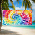 classic spiral tie dye pattern printed on a plush beach towel hanging on a line in a tropical paradise.