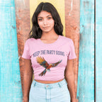 Woman wearing a pink t-shirt with a parrot graphic and text "Keep The Party Going" against a surfboard in the background