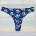 Blue surf bikini bottoms with colorful hand signs on a faded wood background