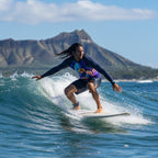 Man wearing a long-sleeve rash guard with a surfboard and floral design surfing Waikiki