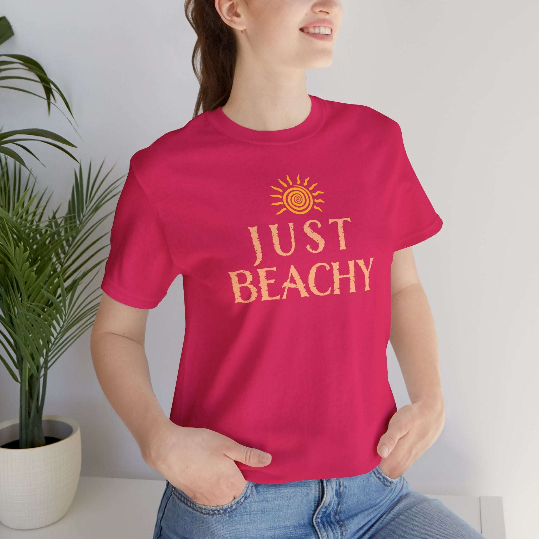 Model wearing a Just Beachy Bella T-Shirt in vibrant pink, perfect for summer vibes and beach lovers.