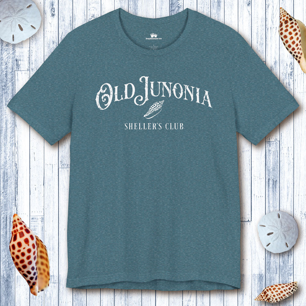 Teal t-shirt with 'Old Junonia Sheller's Club' text on a wooden surface with shells.