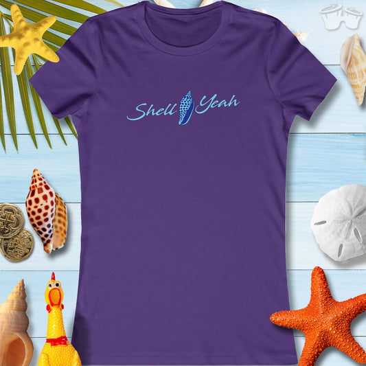 Casual women's tee in purple with 'Shell Yeah' design, surrounded by seashells and beach decor, perfect for summer vibes.