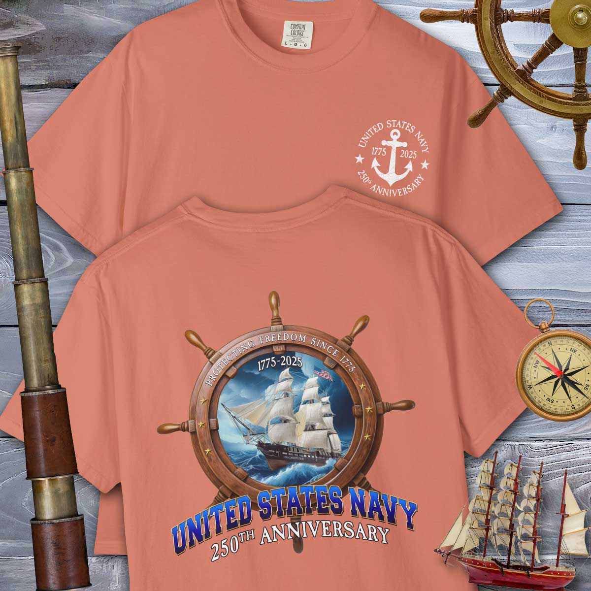 Two peach-colored t-shirts with United States Navy 250th Anniversary designs on a wooden background with nautical items.