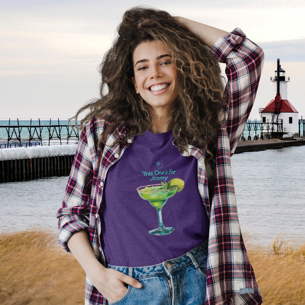 Woman wearing a purple t-shirt with a graphic design by a lighthouse.
