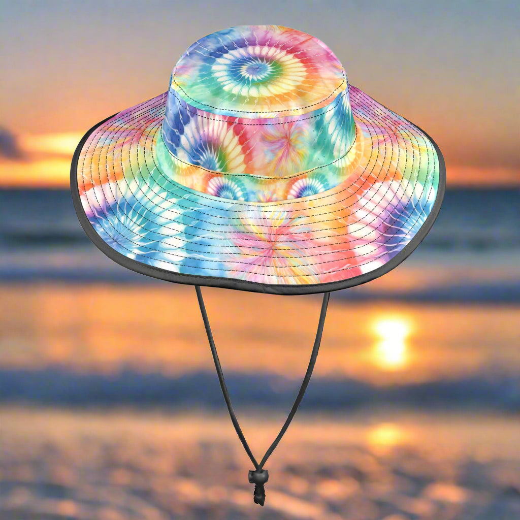 Colorful tie-dye bucket hat with a black chin strap on a white sandy beach