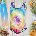Teen Youth Tie Dye One Piece Swimsuit with subtle sharks circling a spiral tie-dye pattern in front of a rustic wood wall and surrounded by surfing icons.
