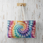 Tie-dye bag with colorful spiral pattern hanging on a wooden hook against a rustic wooden wall.