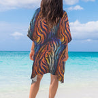 Person wearing a colorful tiger print cover-up on a beach with turquoise water and blue sky.