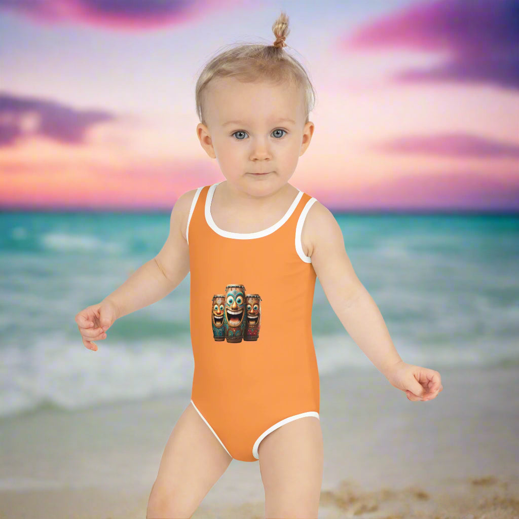 Girl toddler in orange One Piece bathing suit toddling down the beach
