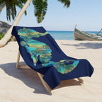 Navy blue beach towel with palm tree design on a wooden lounge chair at a tropical beach.
