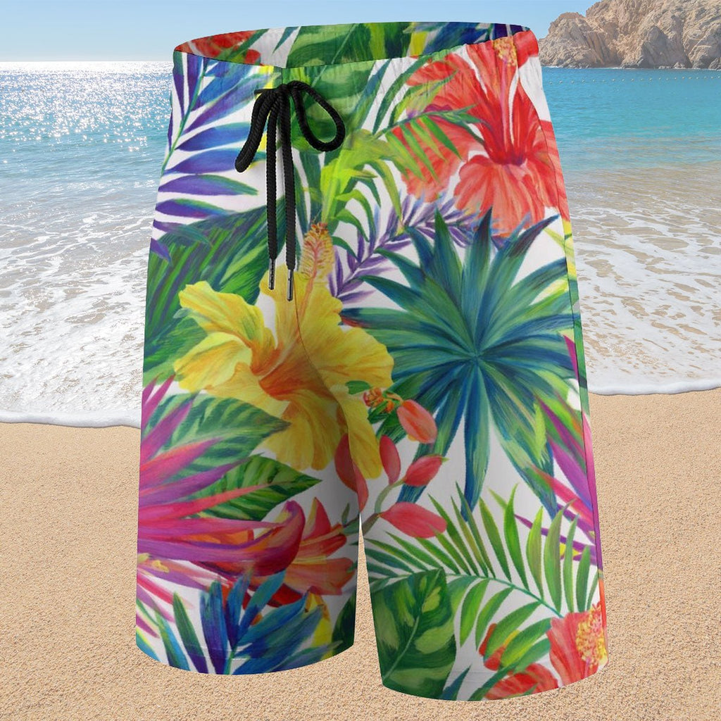 Colorful tropical floral shorts on a sandy beach with ocean in the background