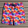 Colorful palm tree patterned shorts laying flat on a rustic wood deck