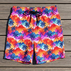 Colorful palm tree patterned shorts laying flat on a rustic wood deck