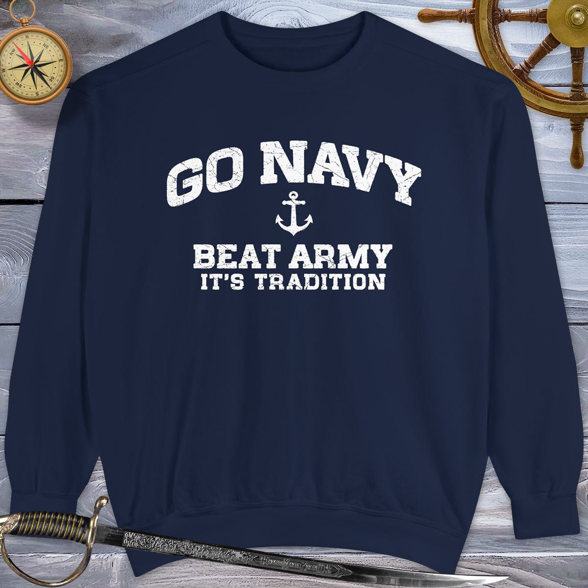 Navy blue Go Navy Sweatshirt with 'GO NAVY BEAT ARMY IT'S TRADITION' text on a wooden background with nautical items.