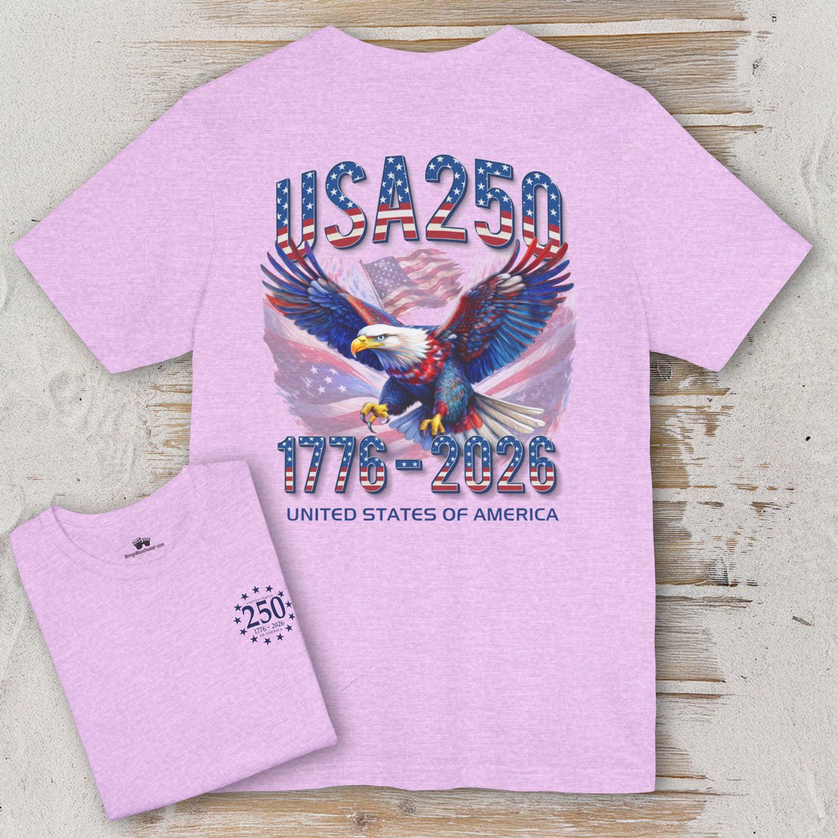 Pink t-shirt with eagle and 'USA 250' design on a wooden surface
