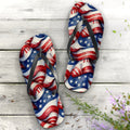 Pair of flip-flops with American flag design on a wooden surface with flowers.