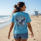 Woman on a beach wearing a USA 250 Anniversary Tee with a Patriotic eagle graphic design and 1776 - 2026 text.