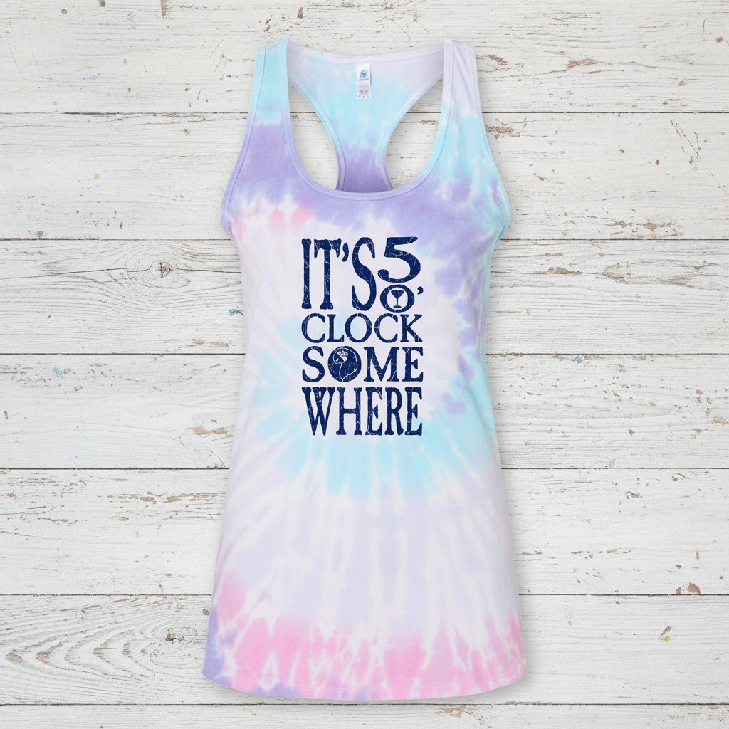 A women's racerback tank top with a pastel tie-dye pattern in purple, blue, and pink, featuring the text 'IT'S 5 O'Clock Somewhere' printed in navy blue on the front.