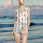 model in a vintage one piece swimsuit with aqua trim is standing on a beach looking for seashells
