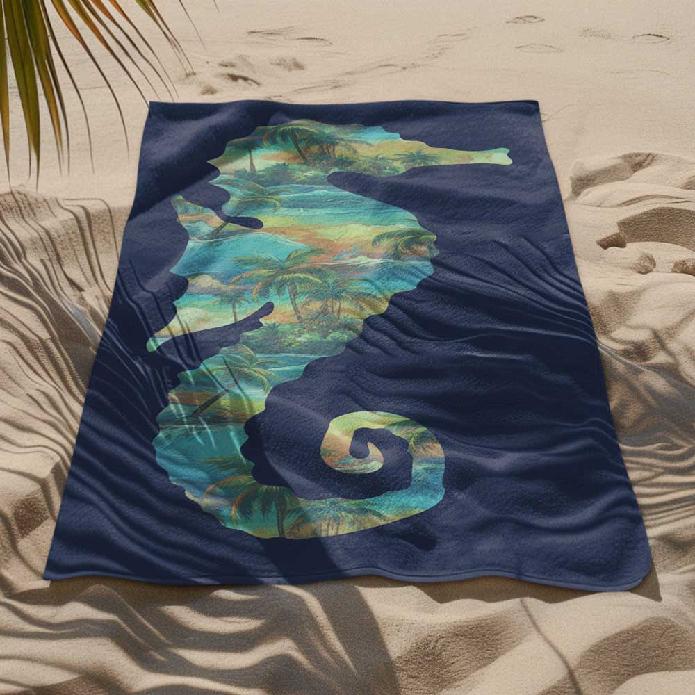 Big Blue Beach towel with vintage seahorse art layin in the sand under a palm tree