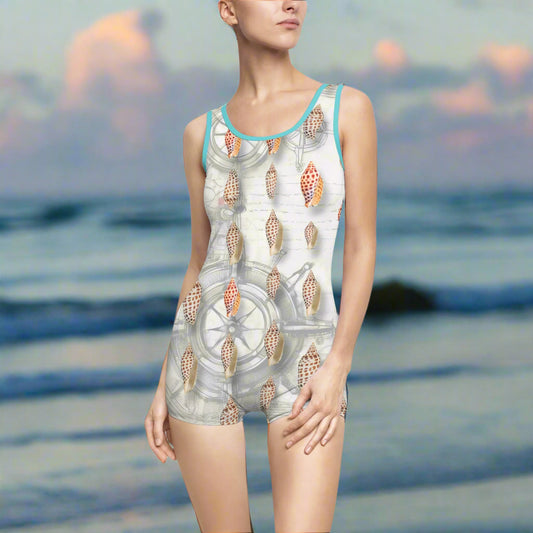 model in a vintage one piece swimsuit with aqua trim is standing on a beach looking for seashells