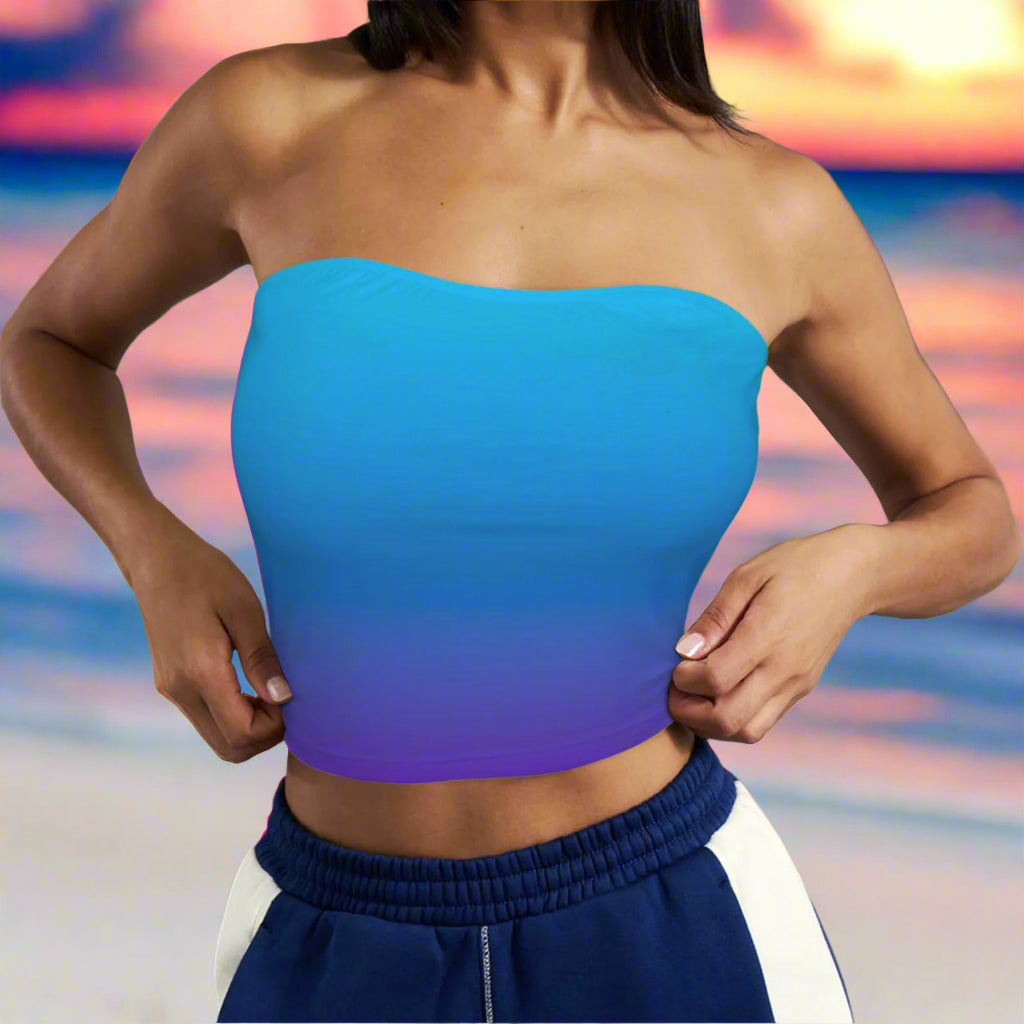 Beachwear model wearing a blue to violet gradient strapless top with a against a beach background