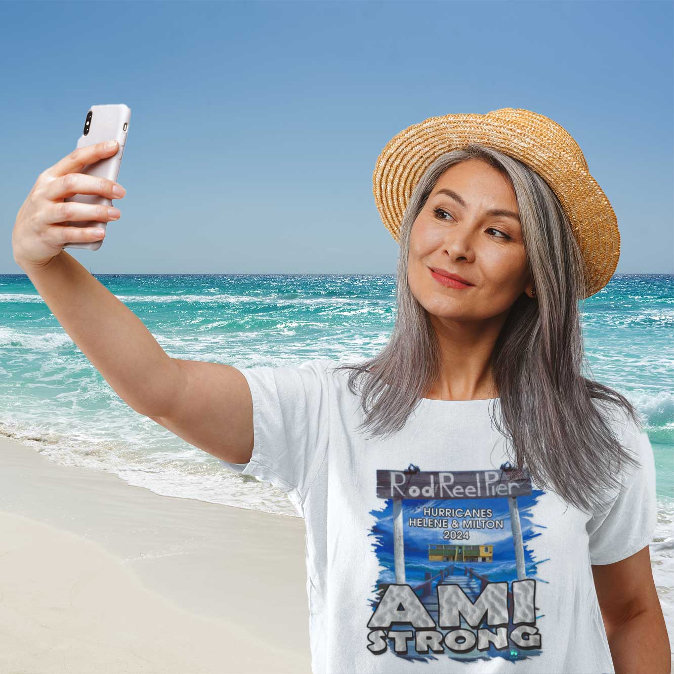 Woman taking a selfie on a beach wearing a 'Ami Strong' t-shirt.