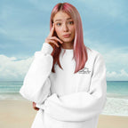 Person wearing a white sweatshirt with text on it, standing on a beach.