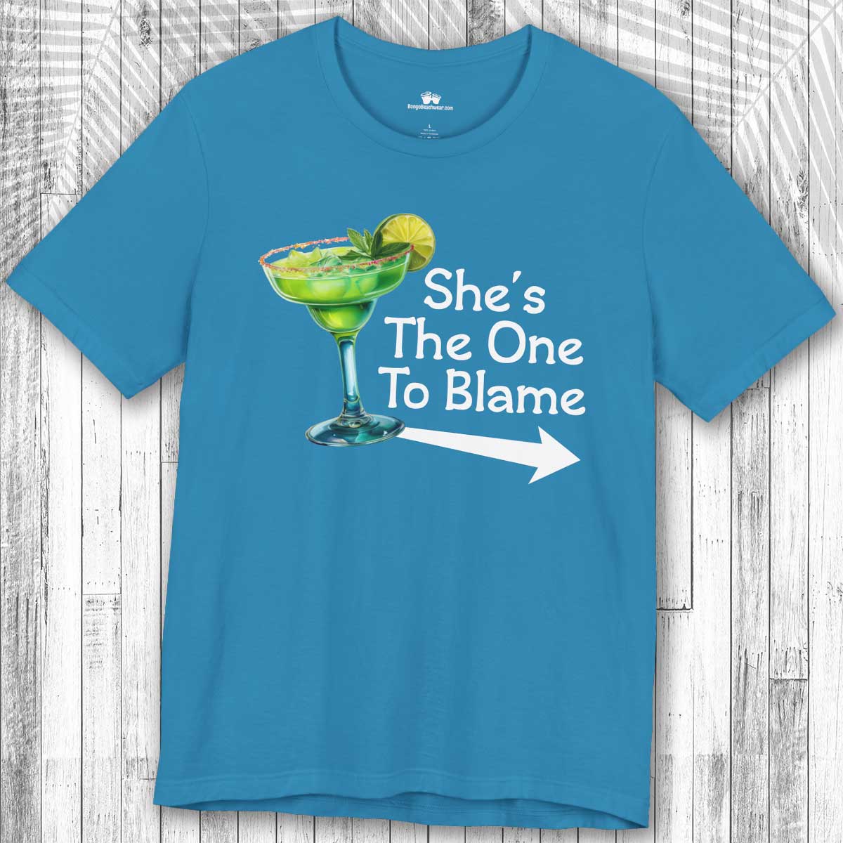 Blue Margarita Party Tee with a graphic of a green cocktail and text 'She's The One To Blame' on a wooden surface.