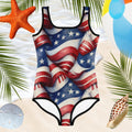 One-piece swimsuit with American flag design on a sandy background with beach elements.
