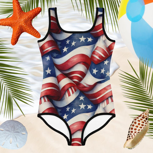 One-piece swimsuit with American flag design on a sandy background with beach elements.
