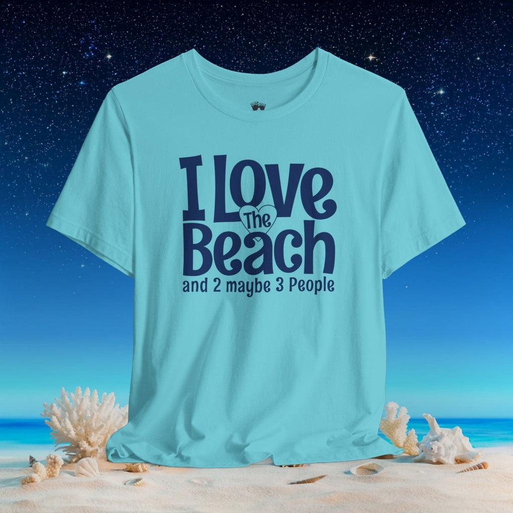 A light aqua blue graphic t-shirt displayed on a beach scene background. The shirt features the text 'I Love The Beach and 2 maybe 3 People' printed in dark navy blue.