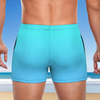 Person wearing turquoise swim shorts with a beach background