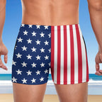 Person wearing swim shorts with American flag design on a beach.