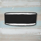 Black headband with white skull and crossbones pattern on a faded wood background